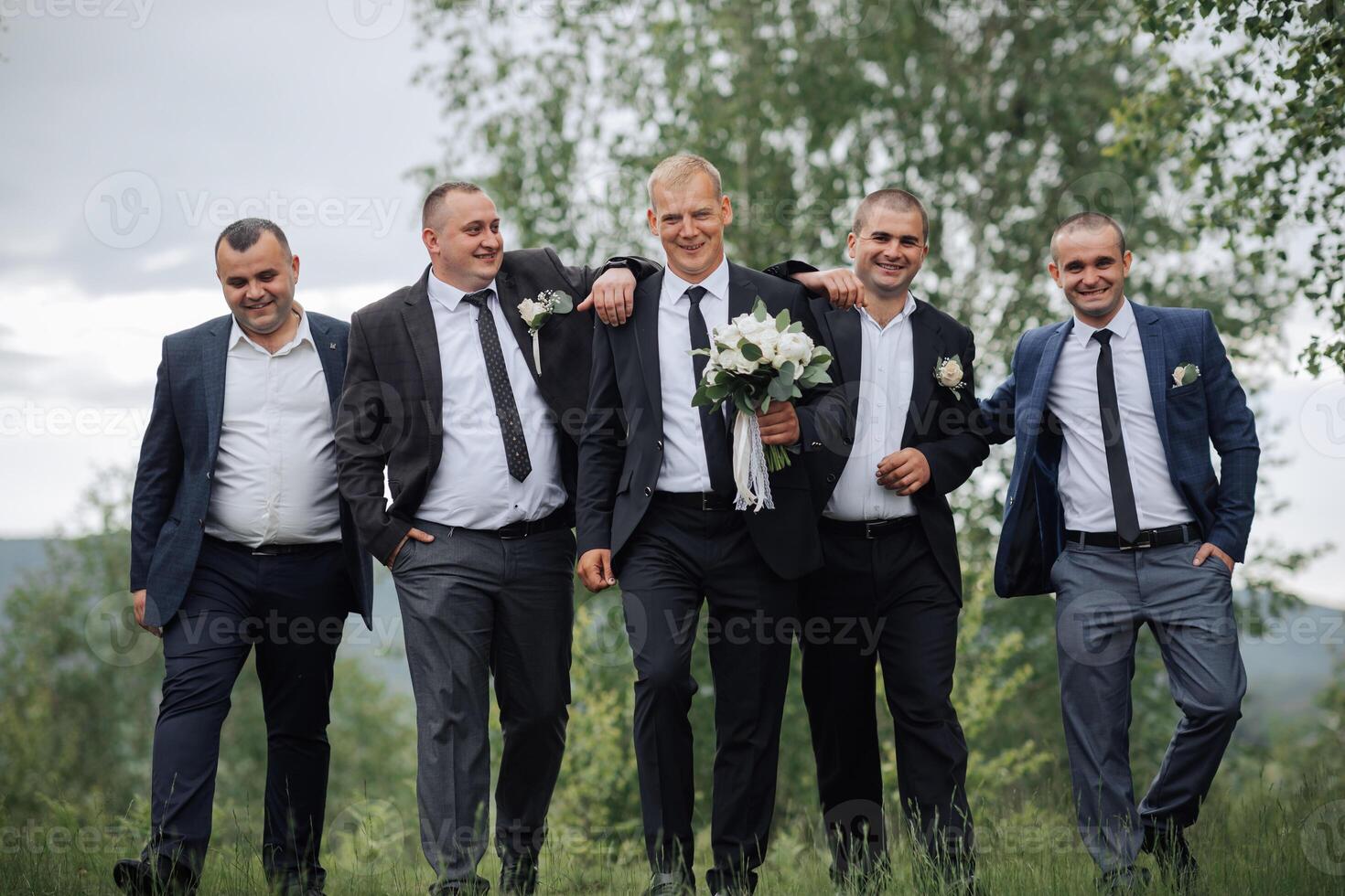 A group of men are dressed in suits and ties, with one man holding a bouquet of flowers photo