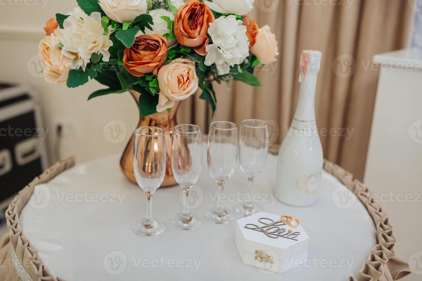 A table with a vase of flowers, four wine glasses, and a white box with the word love written on it photo