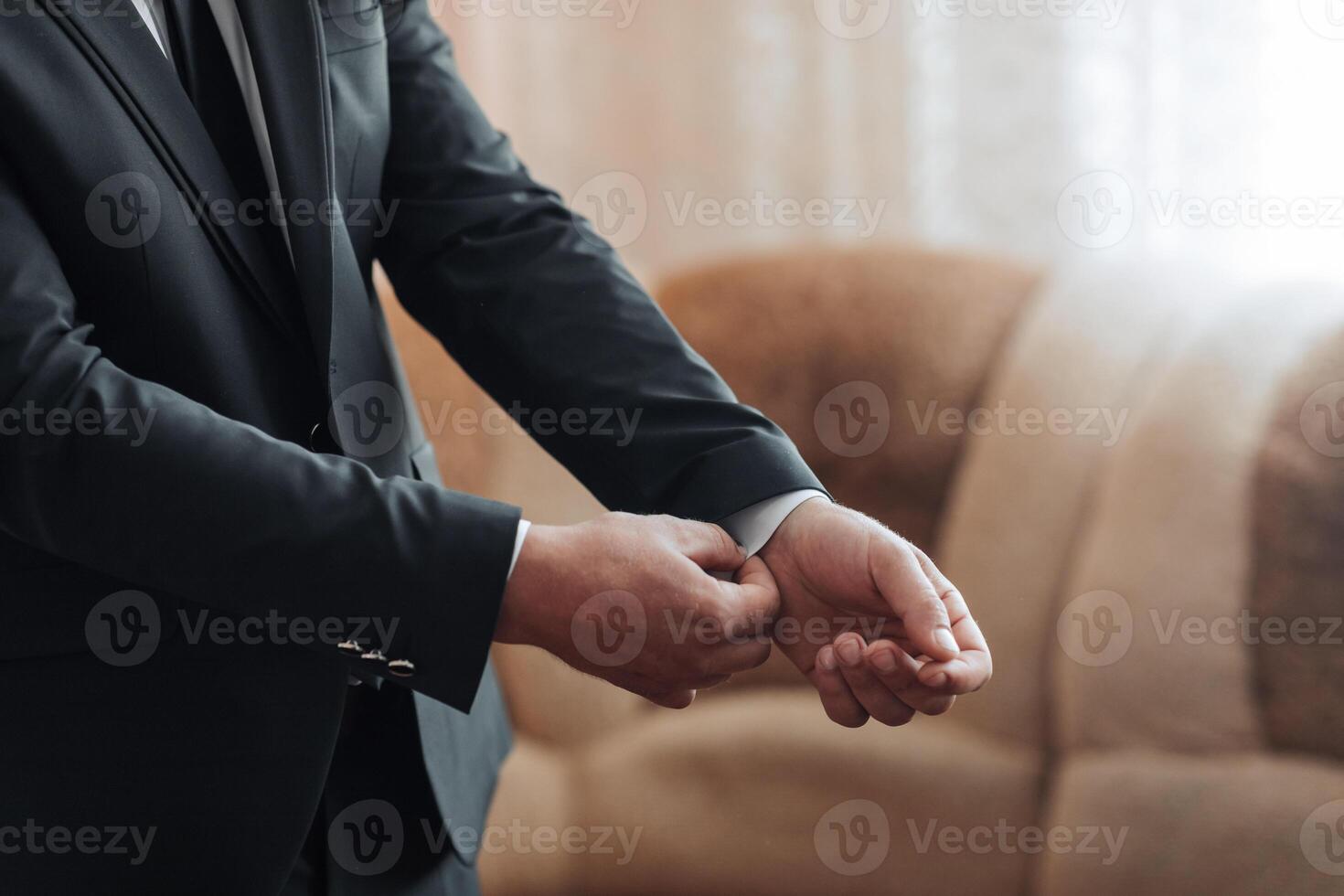 A man in a suit is getting ready for a formal event. He is adjusting his tie and shirt, and his hands are visible. Concept of preparation and formality photo
