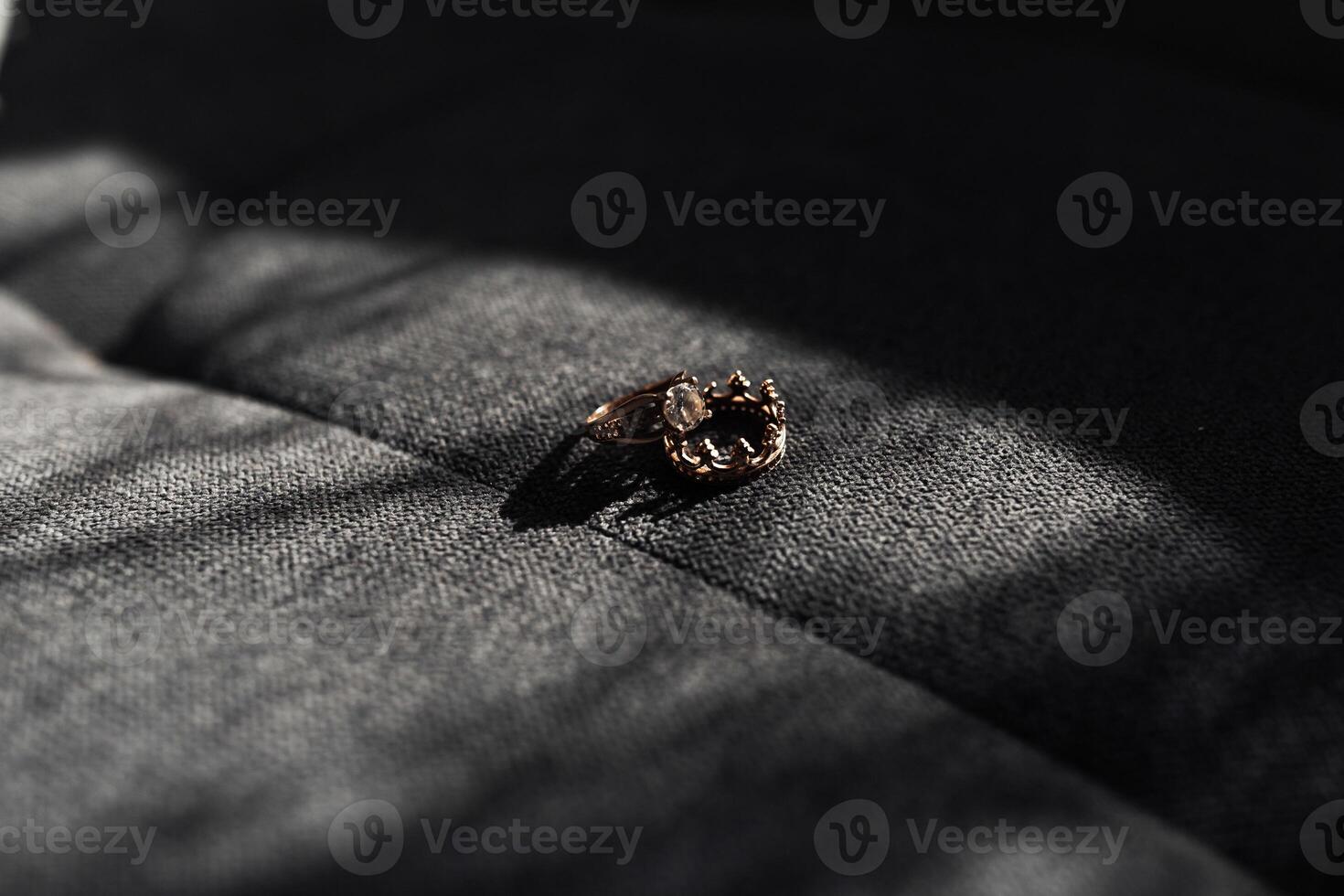 A ring is sitting on a gray surface. The ring is made of gold and has a design on it photo