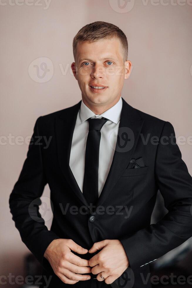 A man in a suit and tie is posing for a photo. He is smiling and he is confident and well-dressed. Concept of professionalism and sophistication, as the man is dressed in a formal suit and tie photo