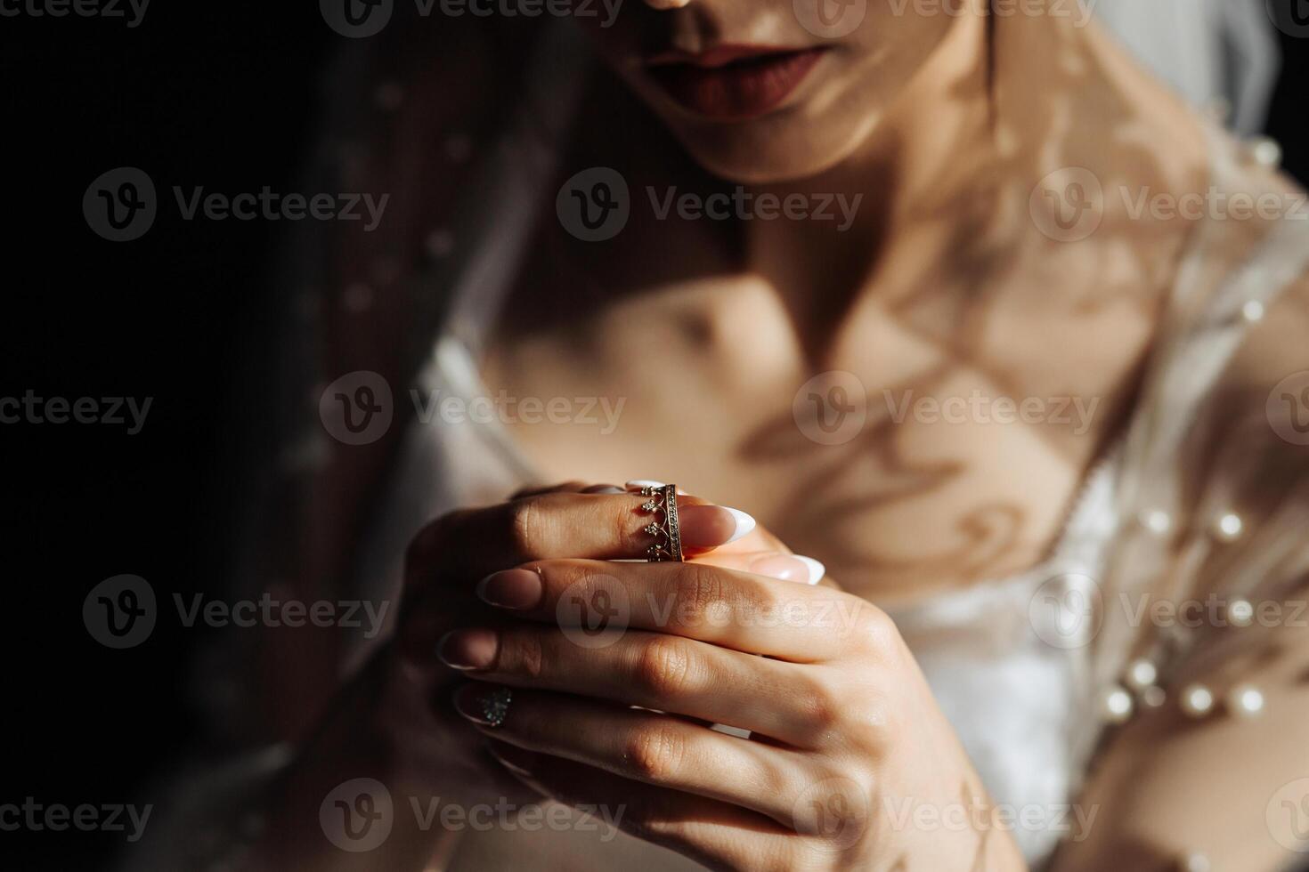 A woman is holding a ring in her hand. The ring is gold and has a diamond in the center. The woman is wearing a white dress and a veil. Concept of elegance and sophistication photo