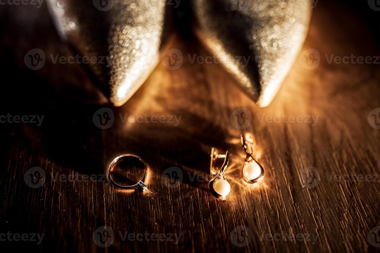 A pair of gold shoes with a ring and earrings on a wooden table photo