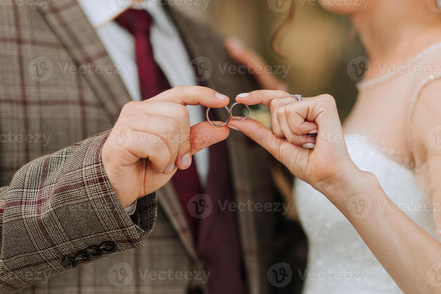 A man and woman are holding rings in their hands, possibly getting married. The man is wearing a suit and tie, while the woman is wearing a wedding dress. Concept of love, commitment, and celebration photo