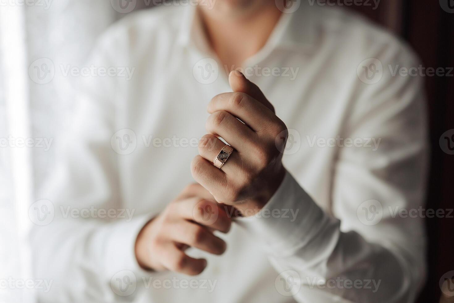 A man is wearing a ring and is holding his hand up to show it photo