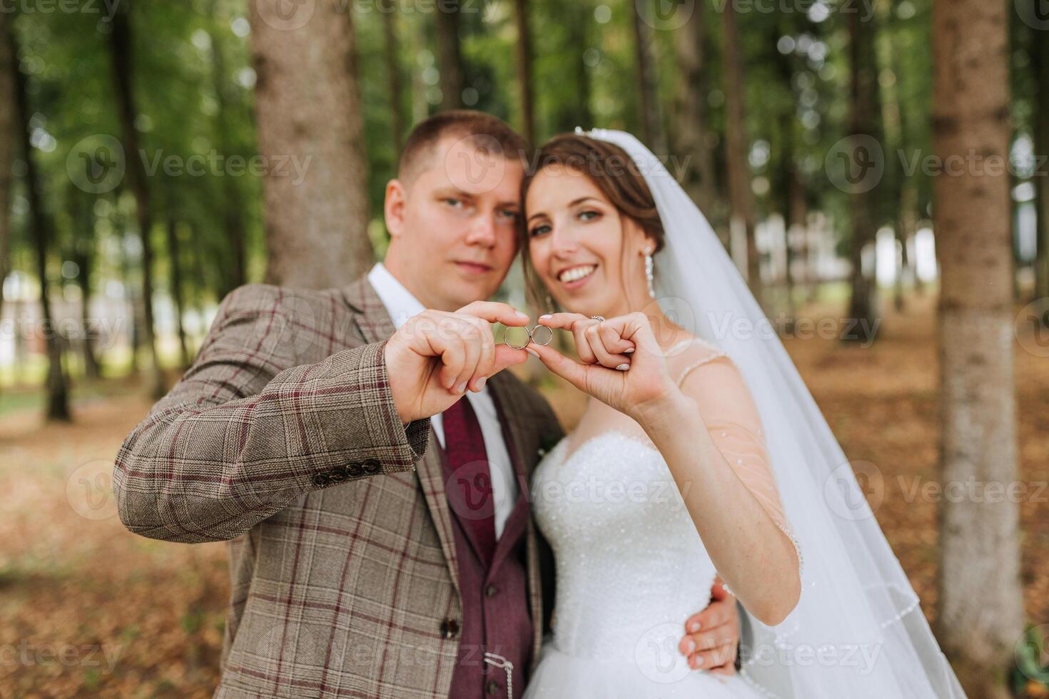 A bride and groom are posing for a picture with their hands together, holding a green ring. Concept of love and commitment, as the couple is celebrating their wedding day photo