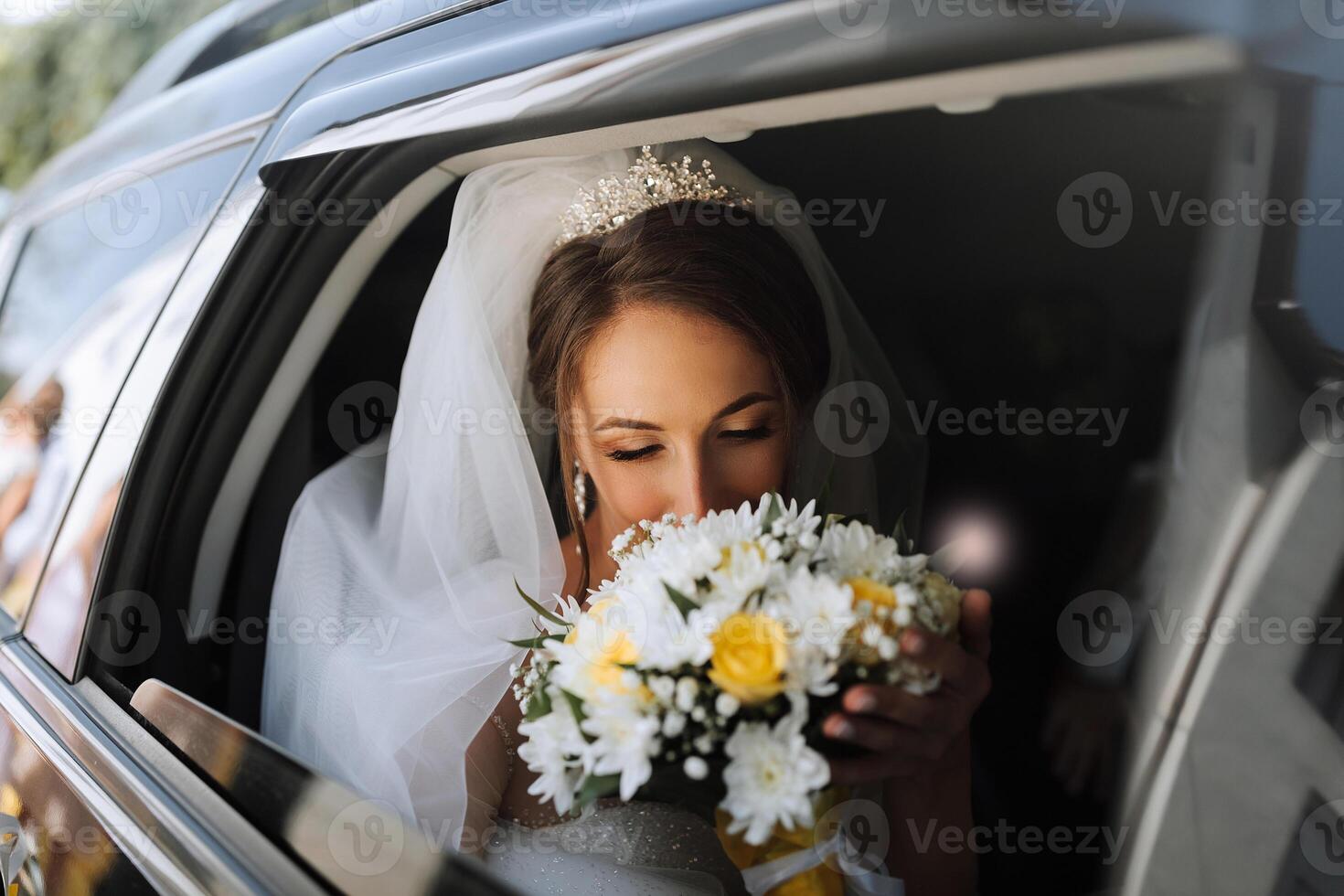 A bride is in a car with a bouquet of flowers. She is holding the bouquet and talking on her cell phone photo