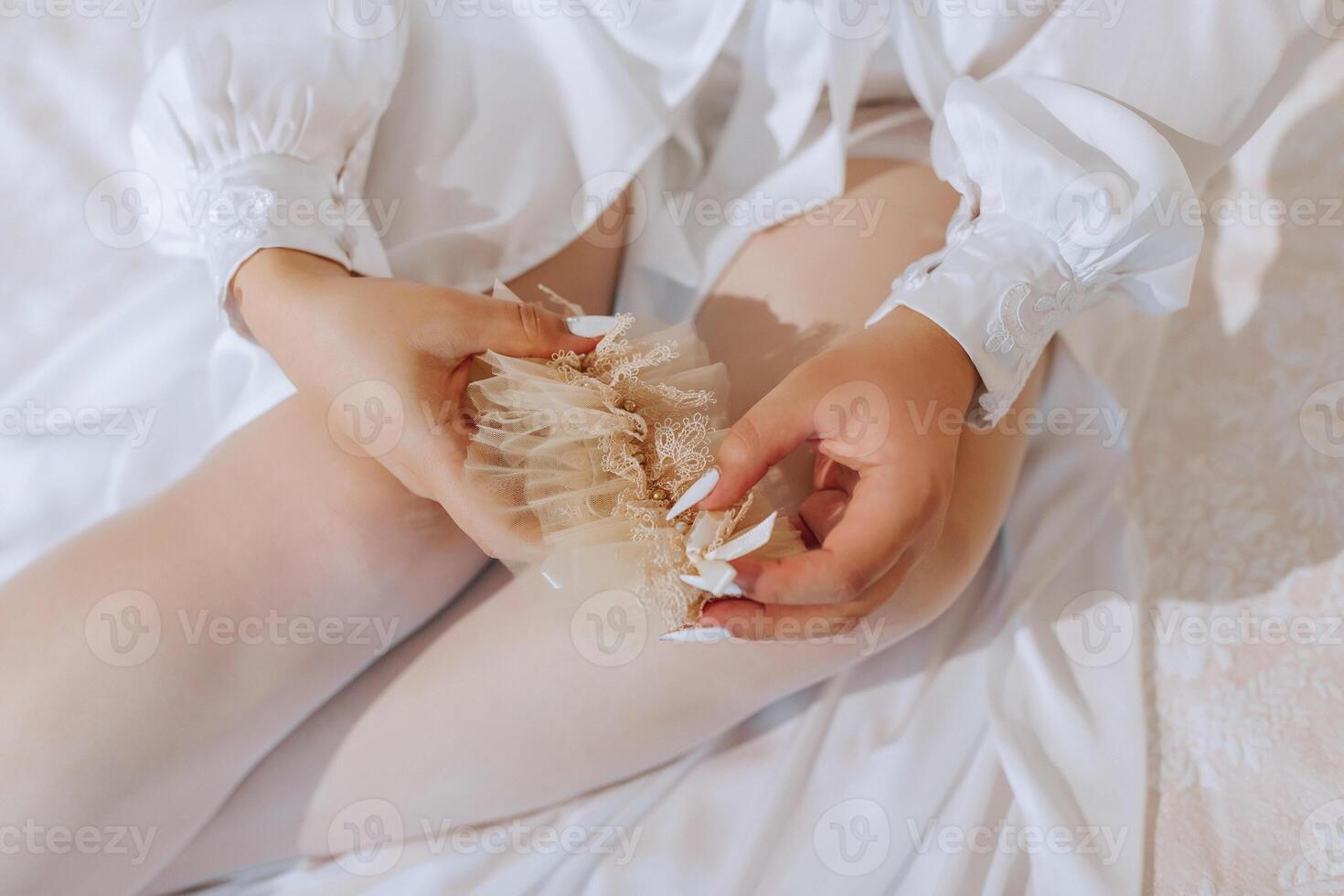 A woman is holding a flower in her hand. The flower is white and has a gold center. The woman is wearing a white dress and is sitting on a bed. Concept of elegance and beauty photo