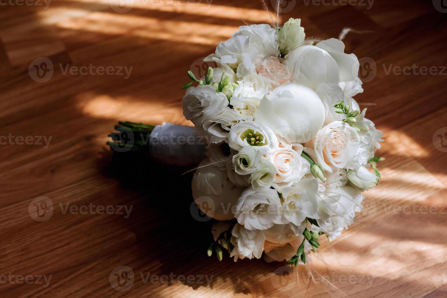 A bouquet of white flowers sits on a wooden table. The flowers are arranged in a way that they are all facing the same direction, creating a sense of harmony and balance photo