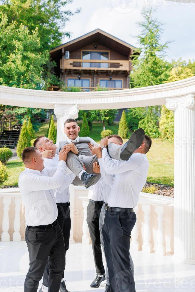 A group of men are playing with a child, one of whom is holding the child. Scene is lighthearted and playful photo