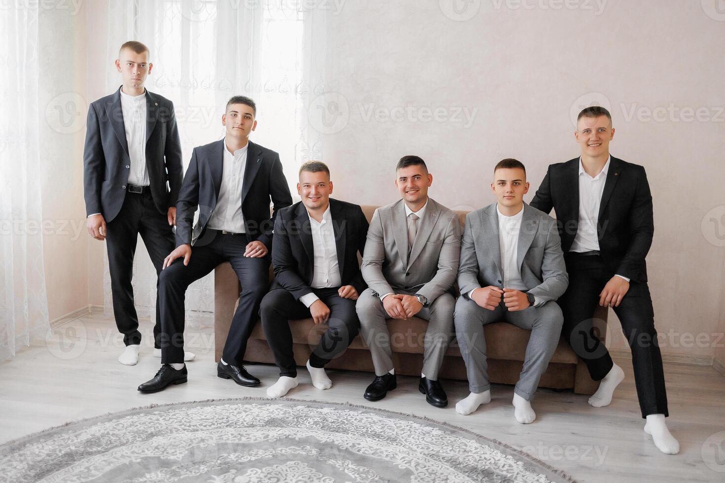 A group of men in suits are sitting on a couch. They are all dressed in black and white photo