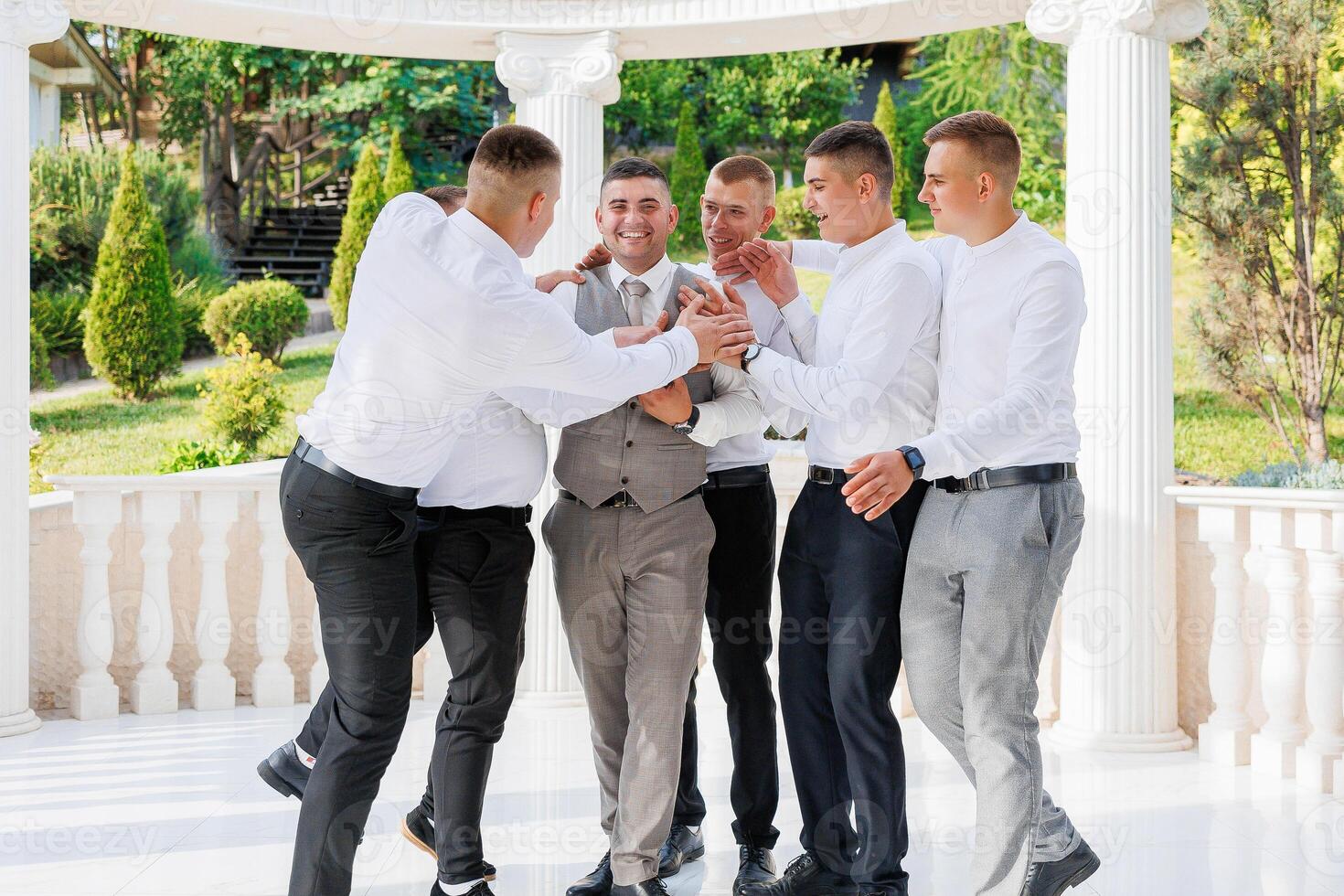 A group of men are standing together, one of them is wearing a tie. They are all smiling and seem to be enjoying each other's company photo