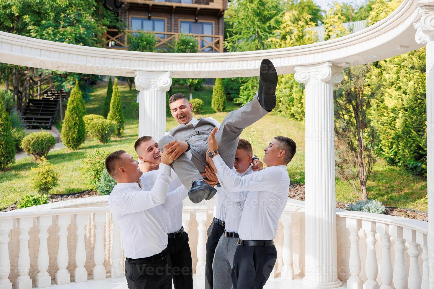 A group of men are playing with each other, one of them is lifting another man. Scene is lighthearted and fun photo
