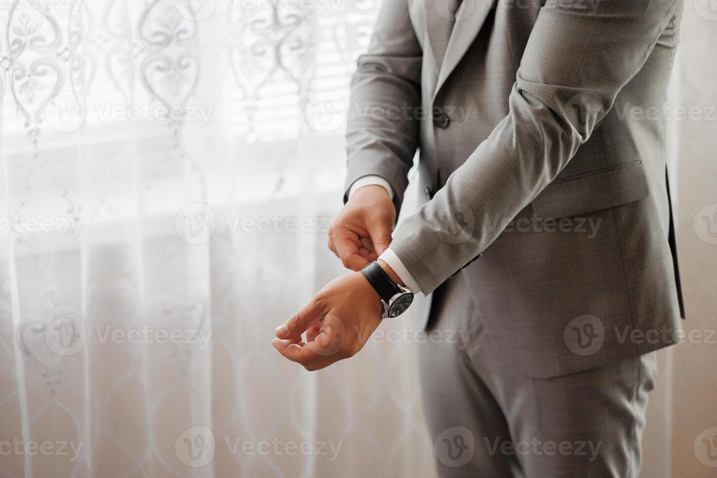 A man in a suit is adjusting his watch. Concept of formality and attention to detail photo