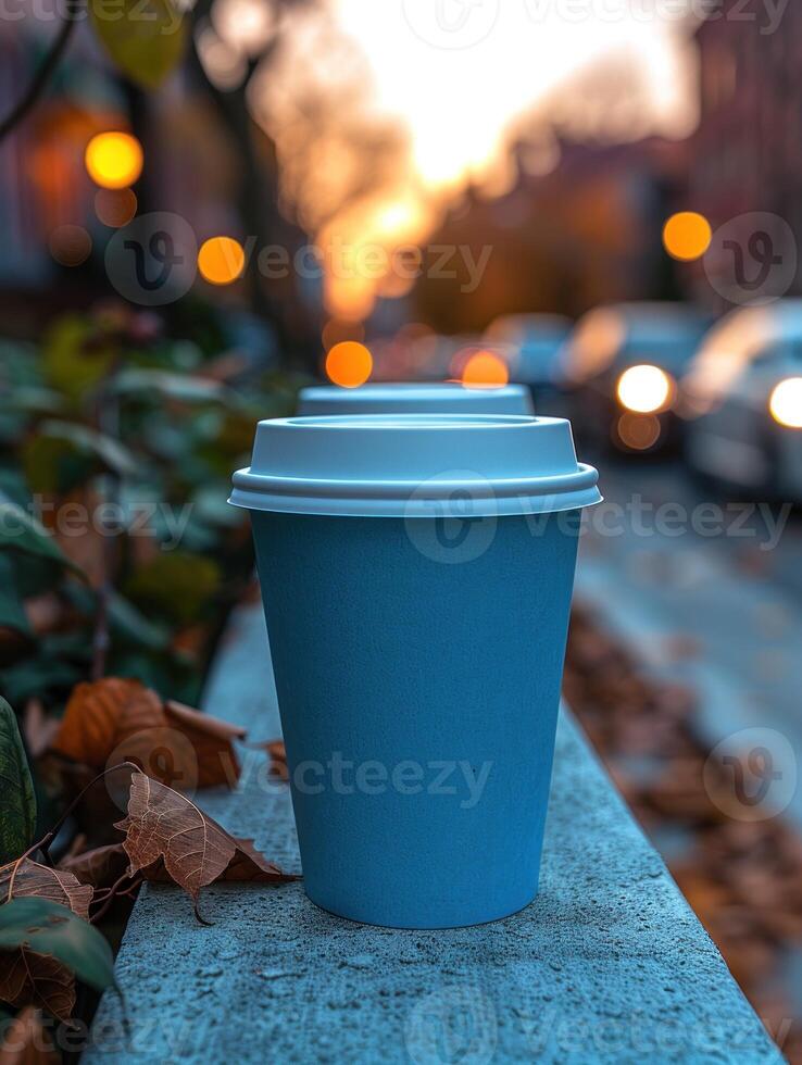 A blue coffee cup sits on a concrete ledge with a soft sunset backdrop photo