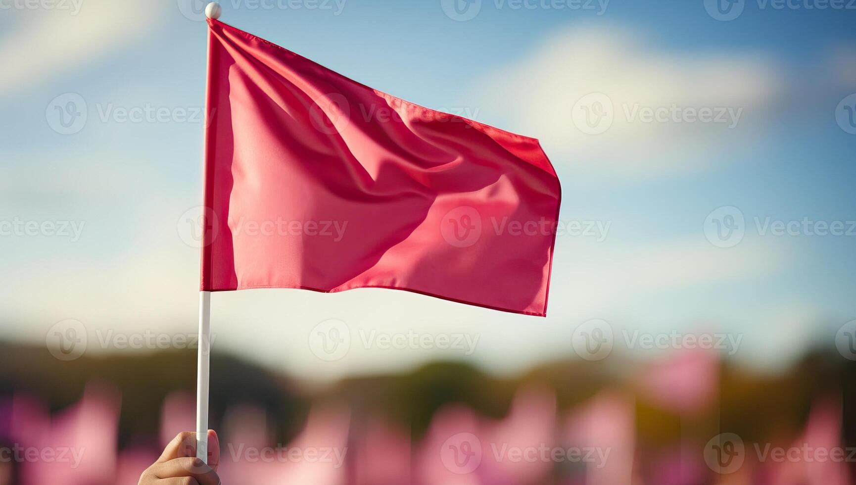 A single red flag waves prominently against a blurred background of pink flags and a blue sky. for signaling, awareness, and standing out. photo