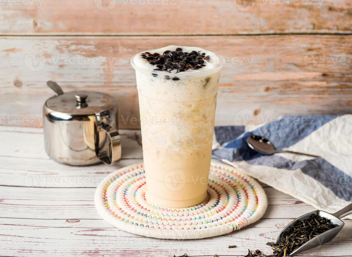 Iced Jasmine Tapioca Green Milk Tea with sugar pot and spoon served in disposable glass isolated on table side view of hong kong tea photo