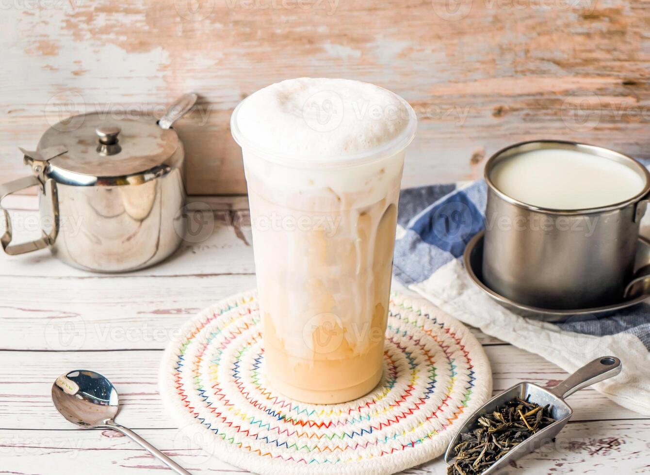 Iced Tieguanyin with Fresh Milk Tea or Tie guan yin with sugar pot and spoon served in disposable glass isolated on table side view of hong kong tea photo