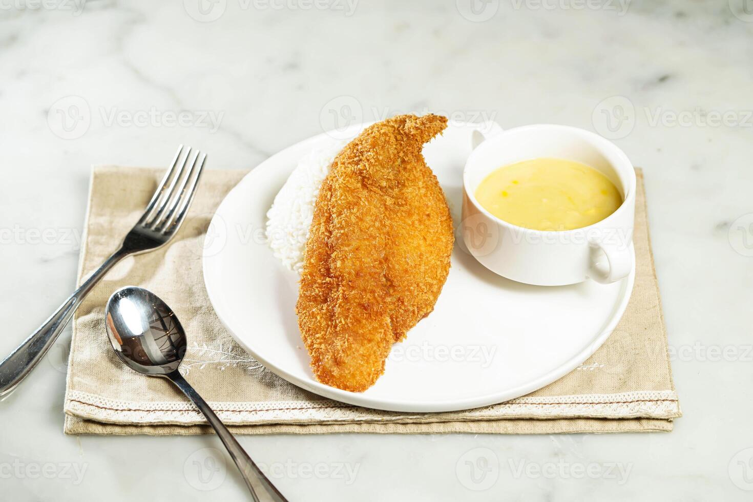 Crispy Fish Fillet with Rice in Sweet Corn Sauce with fork and spoon, served in dish isolated on napkin side view of asian food photo