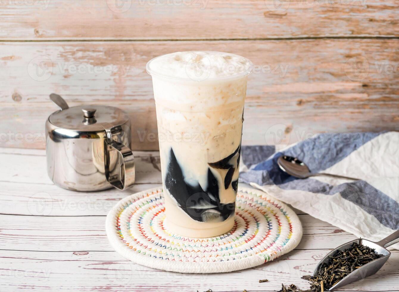 Iced Grass Jelly Green Milk Tea with sugar pot and spoon served in disposable glass isolated on table side view of hong kong tea photo