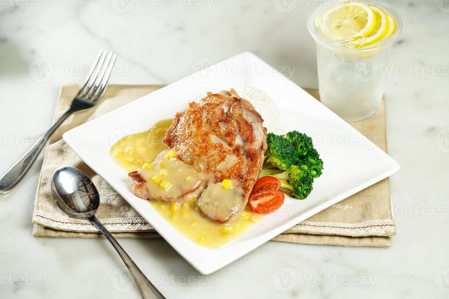 Crispy Chicken Steak with Rice in White Sauce with lemonade, fork and spoon, served in dish isolated on napkin side view of asian food photo