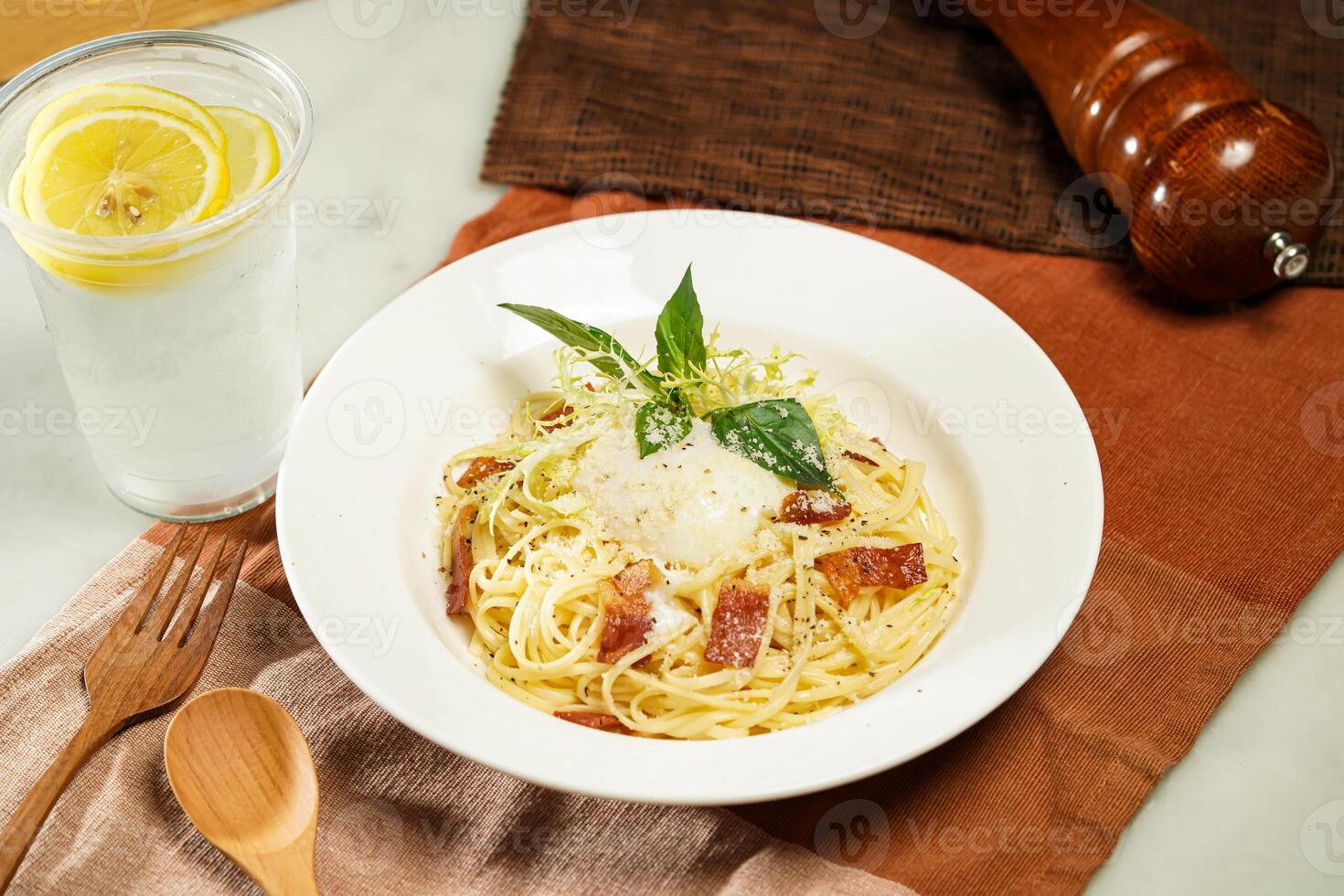 with lemonade, wooden spoon Linguine Carbonara with Soft Boiled Egg or Hot spring egg carbonara pasta and fork served in plate isolated on napkin and dining table side view of italian food photo