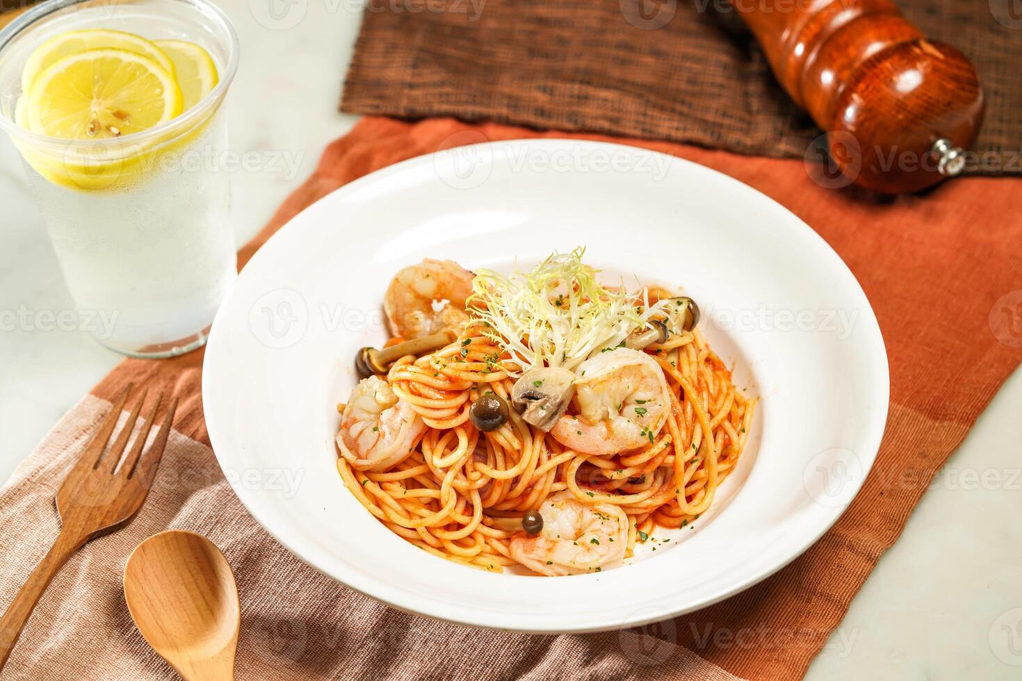 with lemonade, wooden spoon Spaghetti with Shrimps and mushroom in Italian Style and fork served in plate isolated on napkin and dining table side view of italian food photo