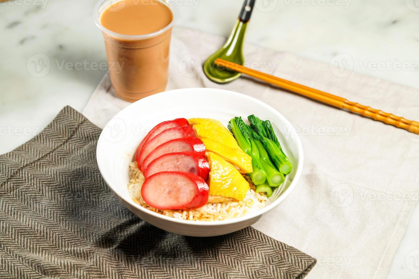 Chinese Sausage and Poached Chicken with Rice with milk kopi chopsticks and spoon served in bowl isolated on napkin side view of hong kong food on marble background photo