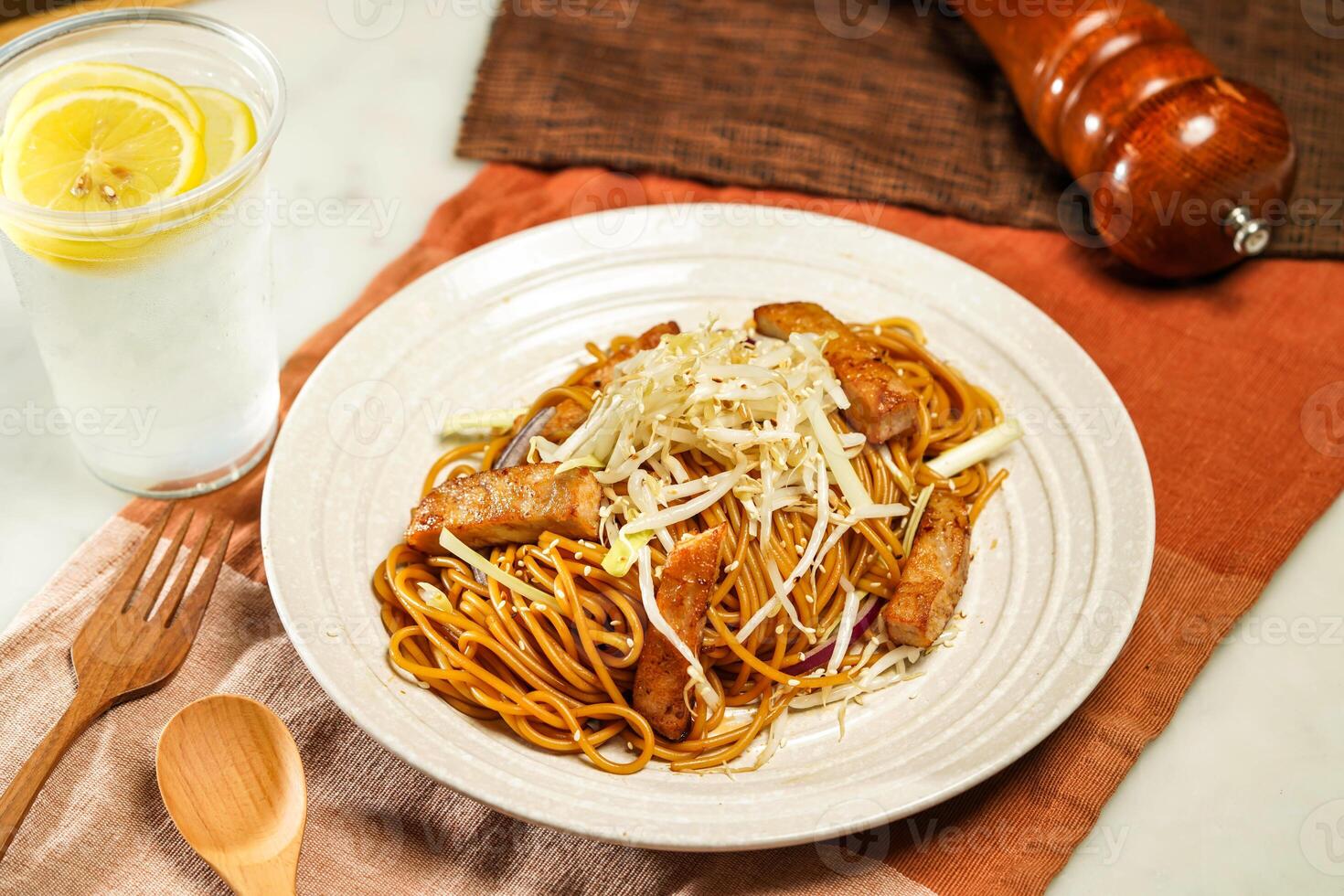 Spaghetti Noodles with Pork Chop in Swiss Sauce with lemonade, wooden spoon and fork served in plate isolated on napkin and dining table side view of italian food photo