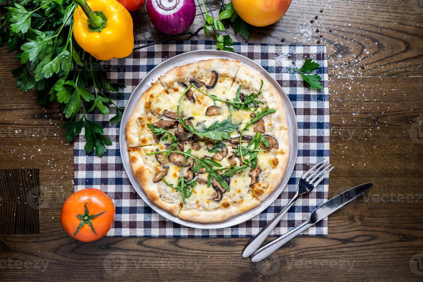 Mushroom Pizza with tomato, onion, capsicum, coriander, knife and fork served in dish isolated on napkin top view of italian fastfood on wooden table photo