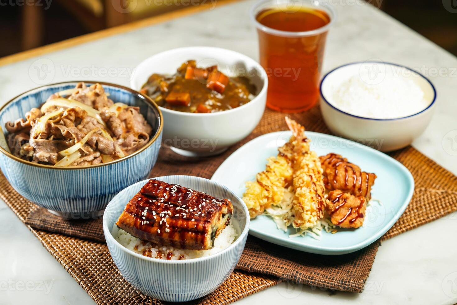 Assorted japanese food verity Teriyaki eel donburi with rice, UMAI Beef Donburi, Deep Fried Chicken and Deep Fried Shrimp Curry rice, and iced tea served on table side view of asian food photo