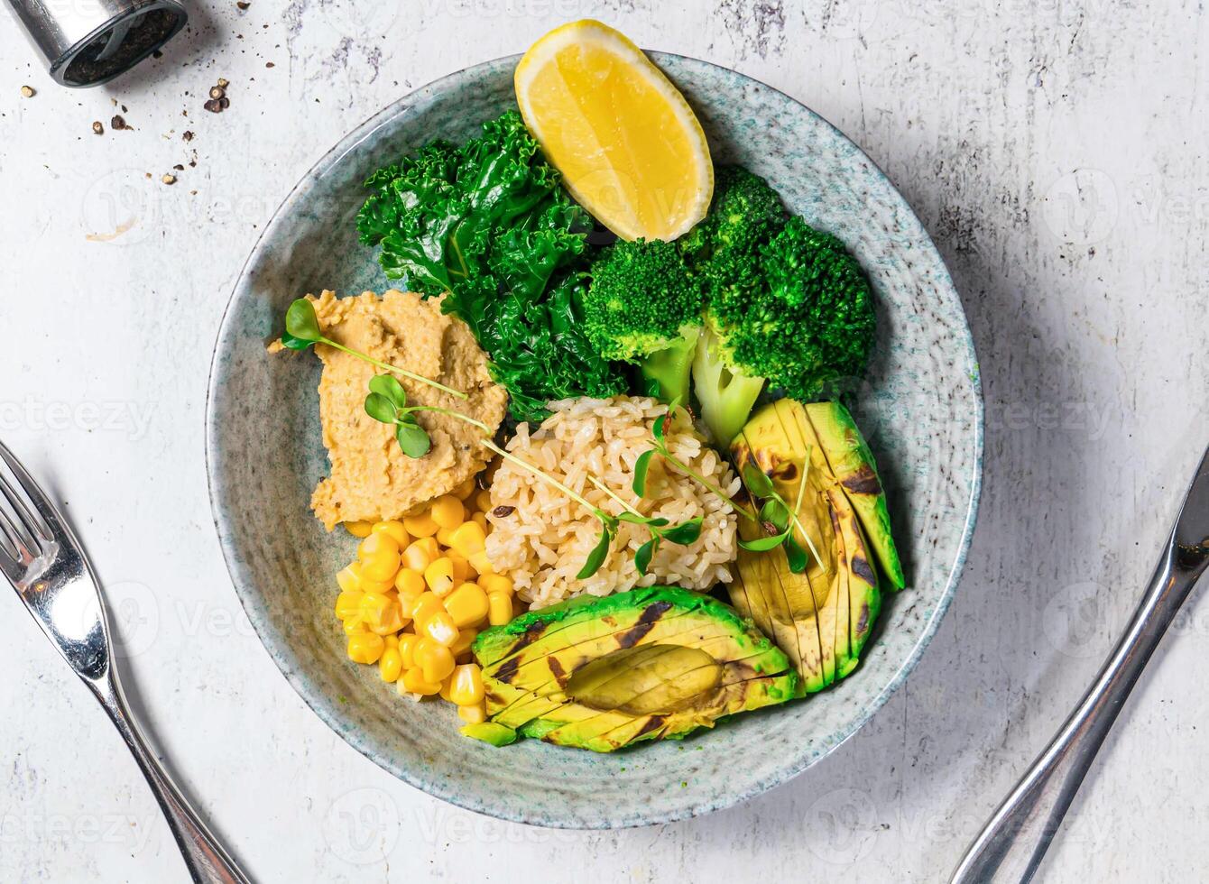 Grilled Avocado Bowl with broccoli, corn, lettuce, fried rice and lemon served in bowl isolated on background top view of italian food photo