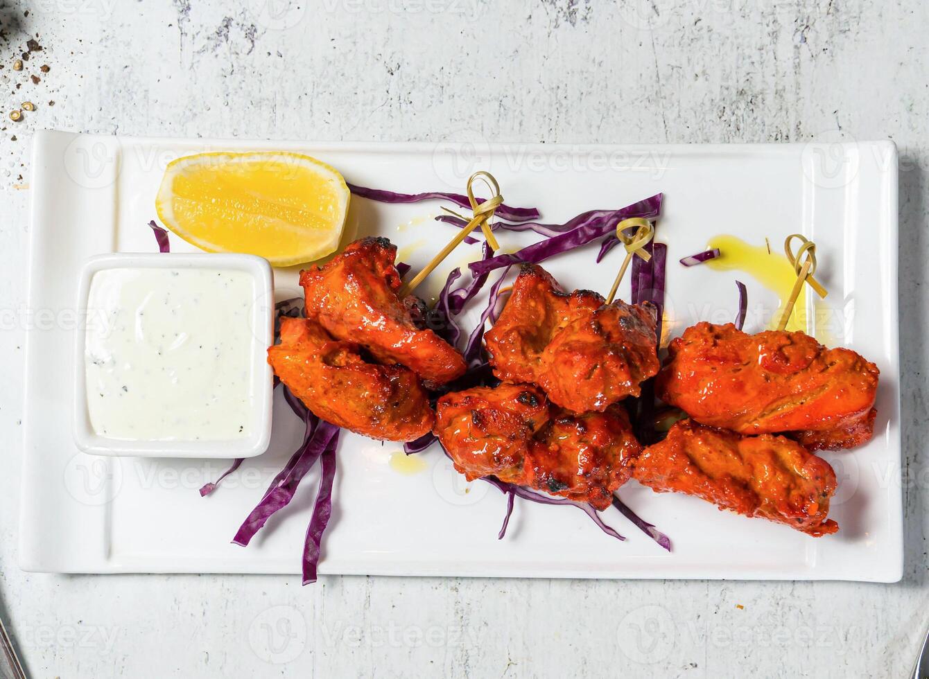 Tandoori Chicken Skewers tikka boti kabab with lemon and sauce dip served in plate isolated on background top view of italian food photo