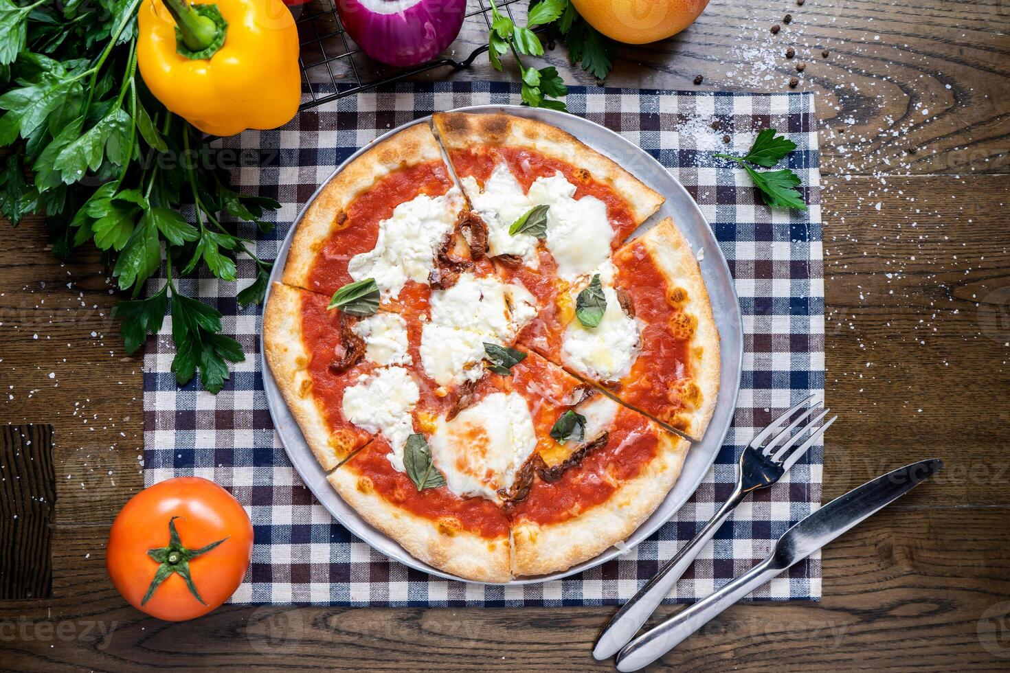 Margherita Pizza with tomato, onion, capsicum, coriander, knife and fork served in dish isolated on napkin top view of italian fastfood on wooden table photo