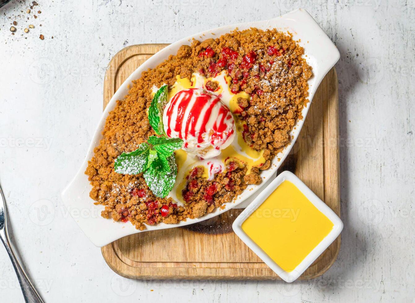 Apple Crumble with vanilla ice cream, mint and dip served in dish isolated on wooden board on background top view of italian food photo