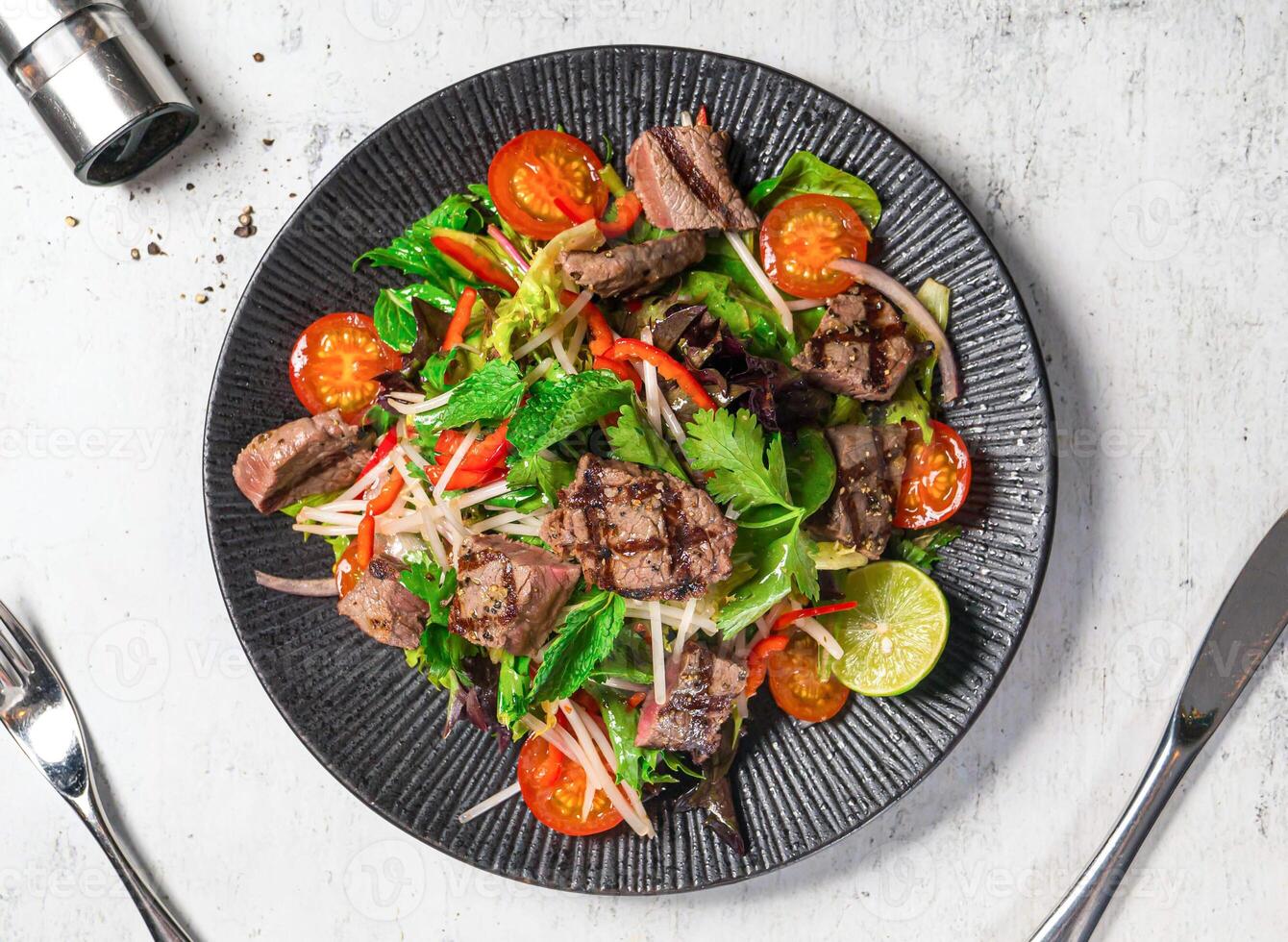 Wagyu Beef Thai Salad with tcherry tomato, onion, lemon, mint and coriander served in plate isolated on background top view of italian food photo