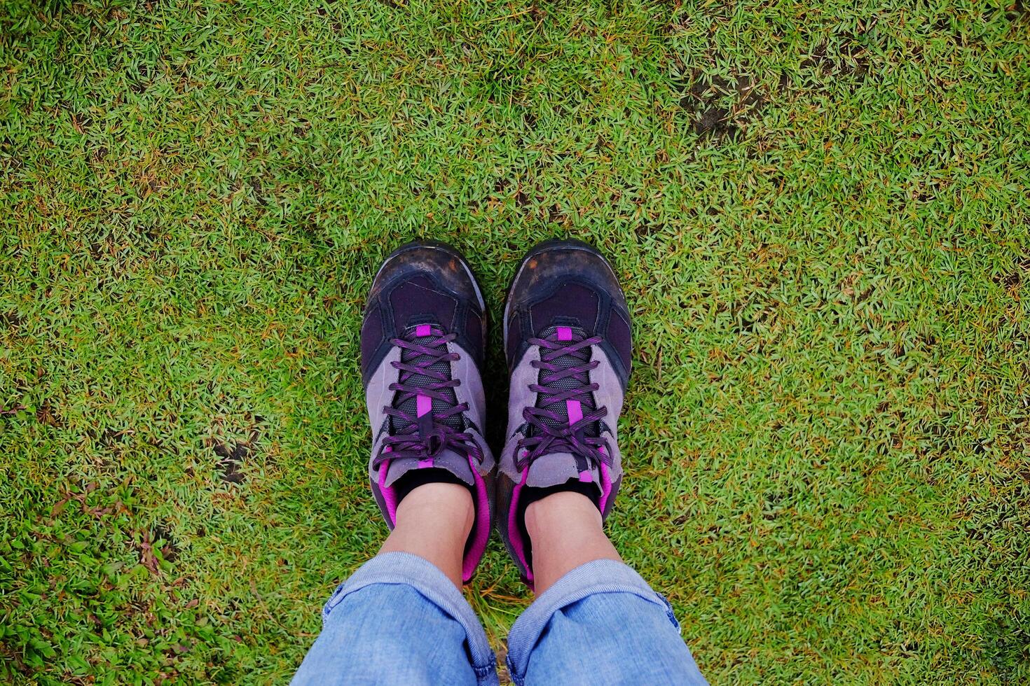 Top view selfie of woman feet and black sneaker stand on the grass field in tropical garden photo