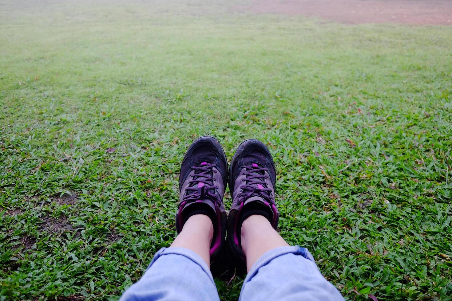Top view selfie of woman feet and black sneaker stand on the grass field in tropical garden photo