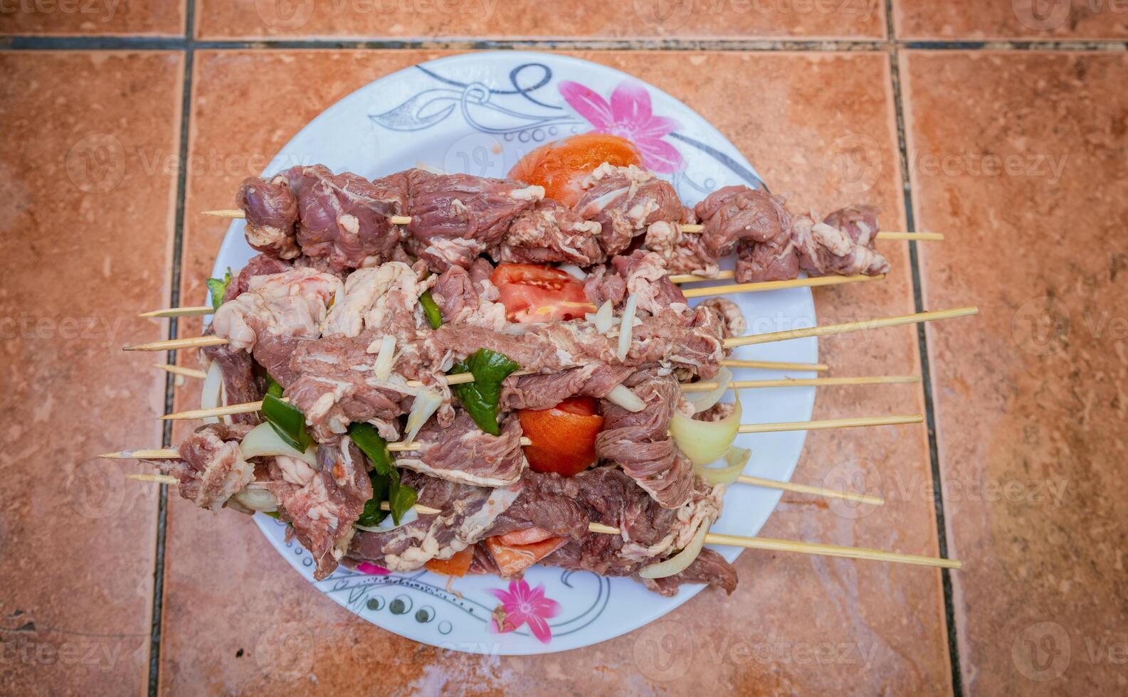 Raw beef skewers on a plate. Preparation of raw beef skewers. Fresh and raw beef skewers on a plate. Close up of raw beef meat skewers with ingredients photo