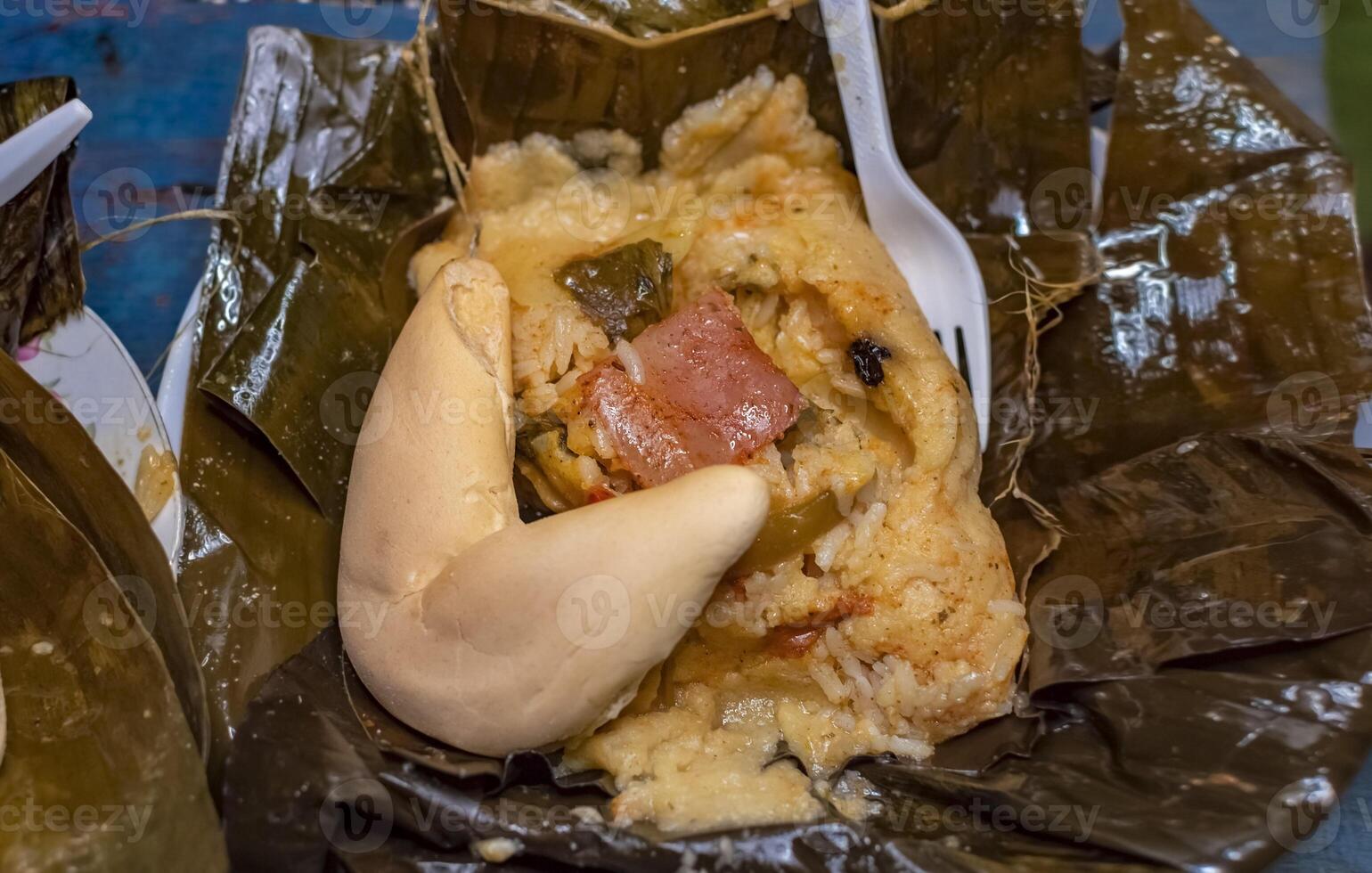Nacatamal served with bread in a banana leaf on the table. Traditional Nacatamal served in banana leaf, Nicaraguan Nacatamal with bread on the table, Traditional Venezuelan Hallaca served photo