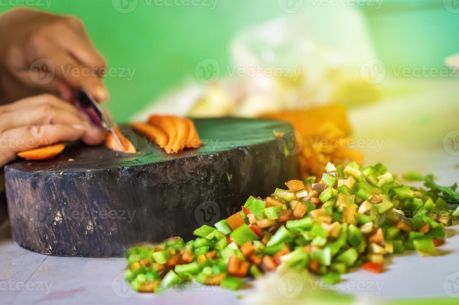 Hands cutting carrot pieces on a homemade chopper. Close up of hands chopping carrots in a wooden chopper. Concept of hands cutting vegetables in a wooden chopper photo