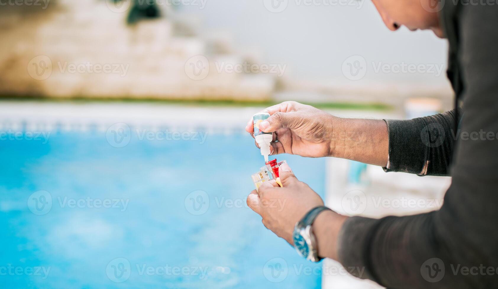Man using tester kit to measure chlorine and ph in swimming pools. Person testing the PH of the swimming pool photo