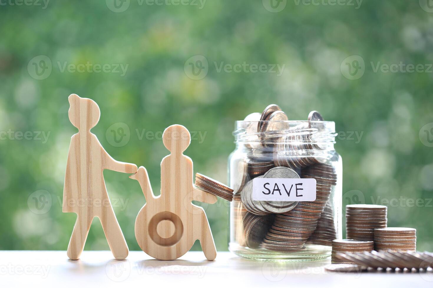 Employee volunteer assistant with man on wheelchair and coin money in the glass bottle on natural green background,Save money for prepare in future and handicapped person concept photo