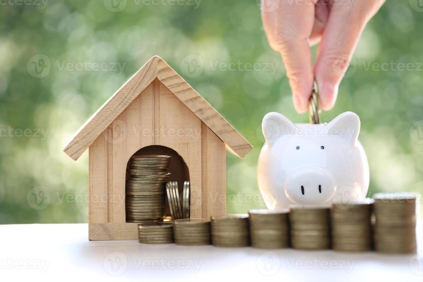 Finance, Model house with piggy bank and stack of coins money on natural green background,Business investment and real estate concept photo