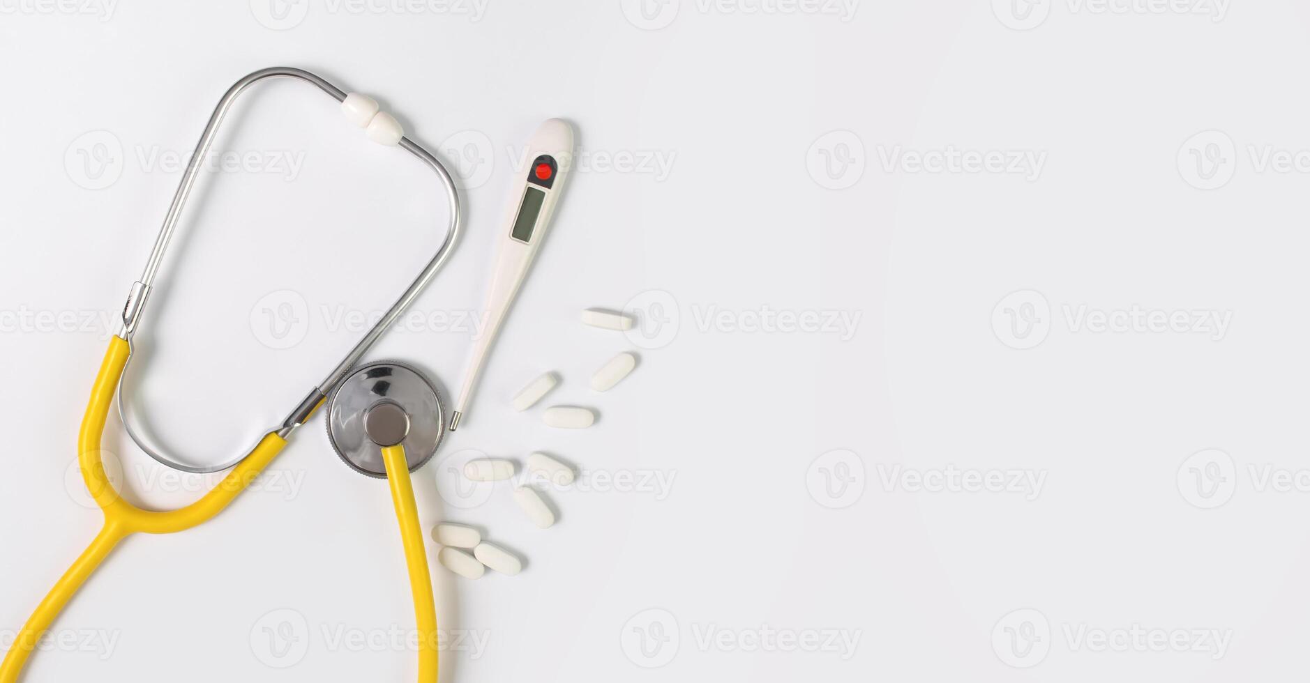 Yellow stethoscope and thermometer on a gray background. Concept of medicine. Health Day. Copy space. photo