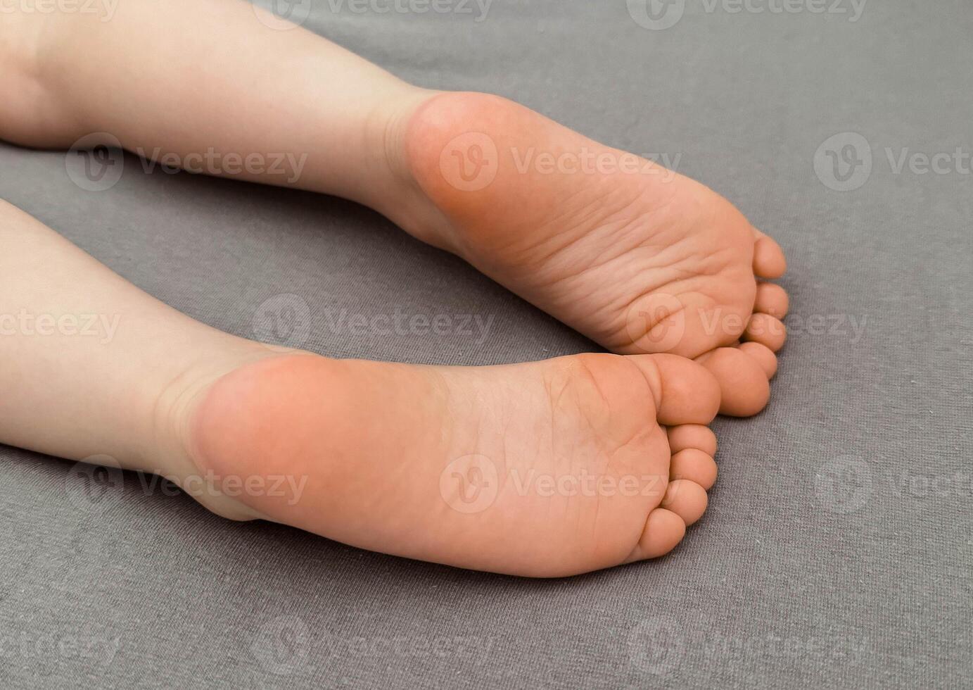 Children's bare feet on the bed, on the gray sheet. Photo of Cute feet of a sleeping baby.