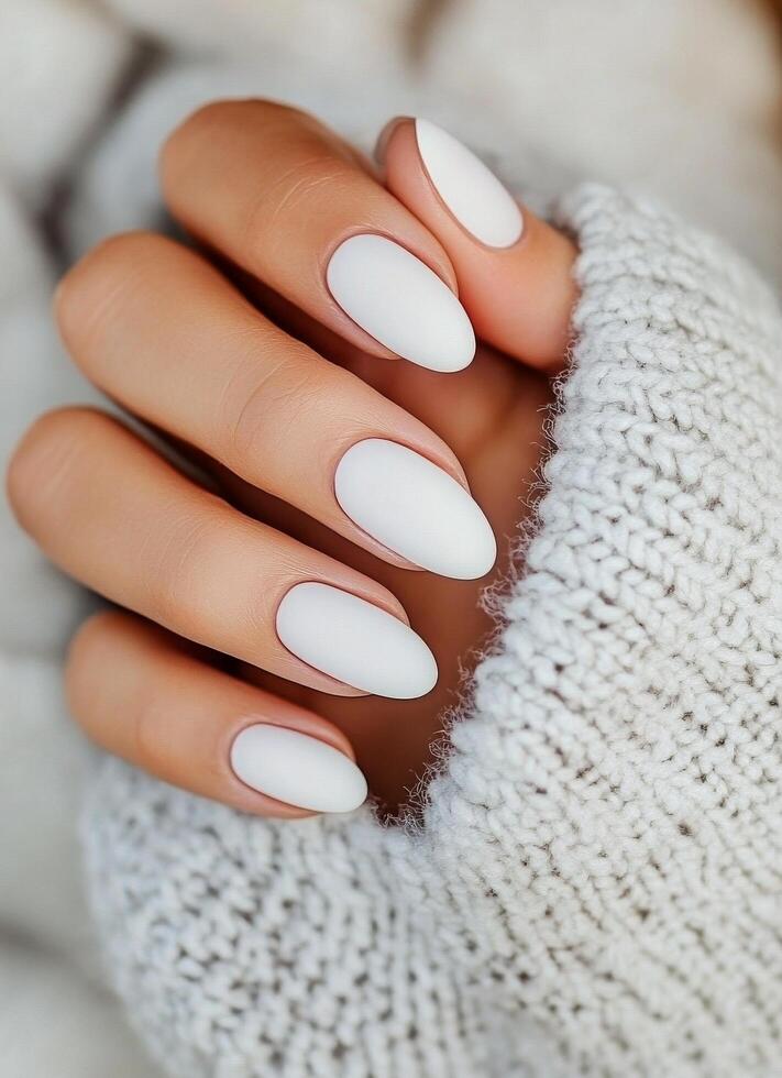 Elegant white nail design showcased with a cozy knitted sweater in a warm indoor setting photo