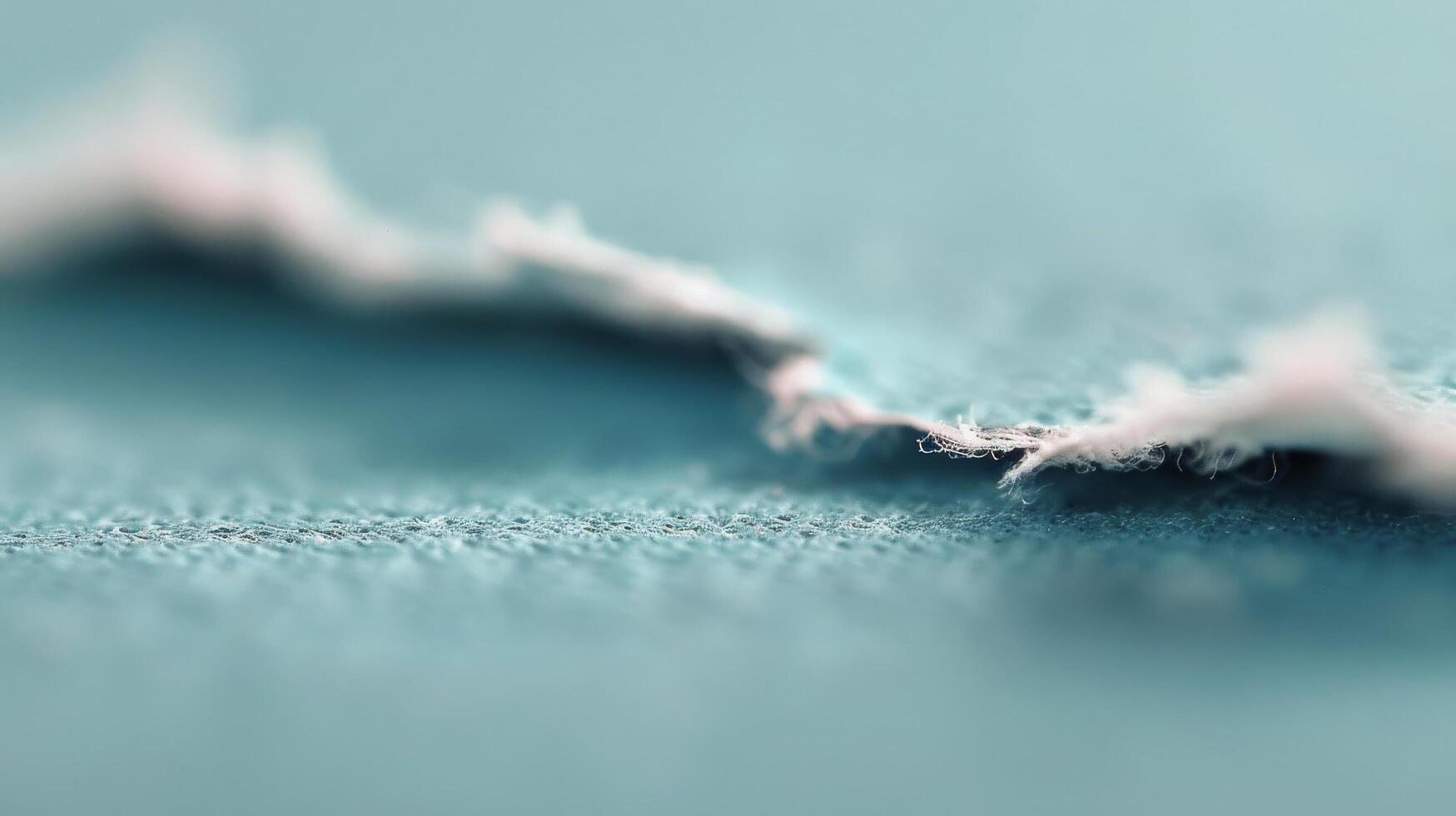 Close-Up View of Frayed Fabric Edge on Soft Blue Material photo