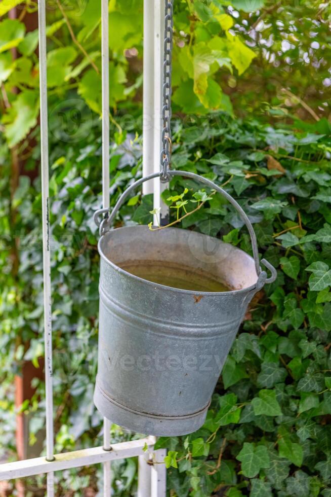 bucket hanging from a chain is filled with water photo