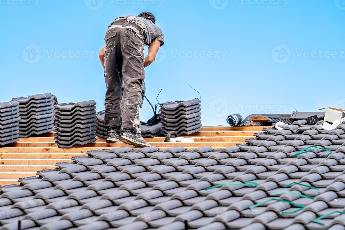 workman installs a fired ceramic tile on the roof of family house photo
